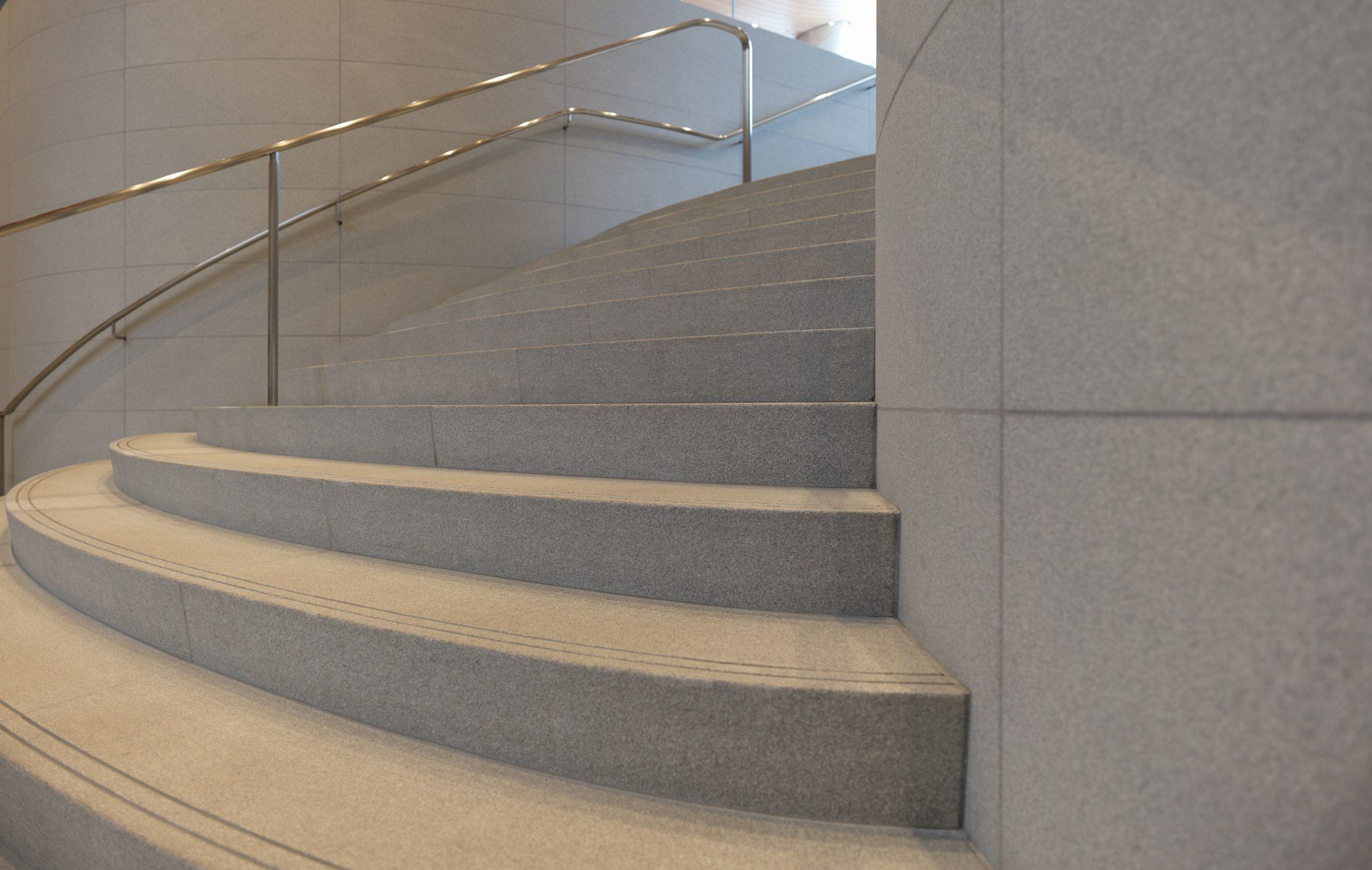A curved stone staircase with a steel handrail