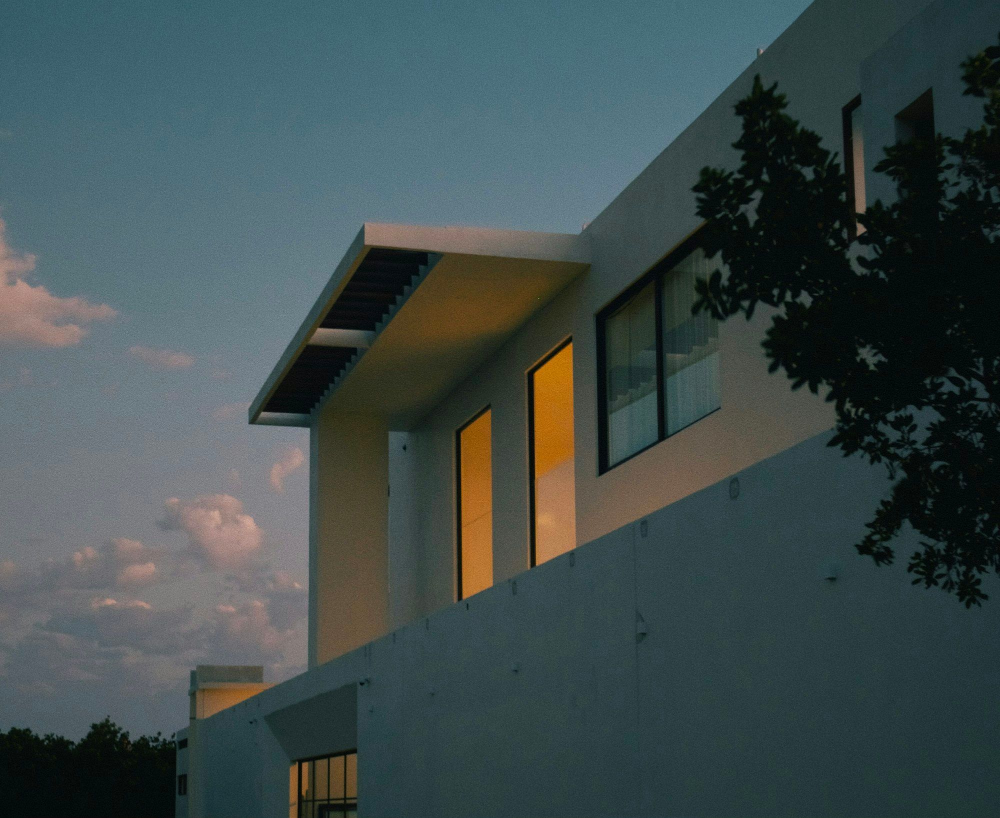 Alacakaranlıqda işıqlı pəncərələri olan müasir villa